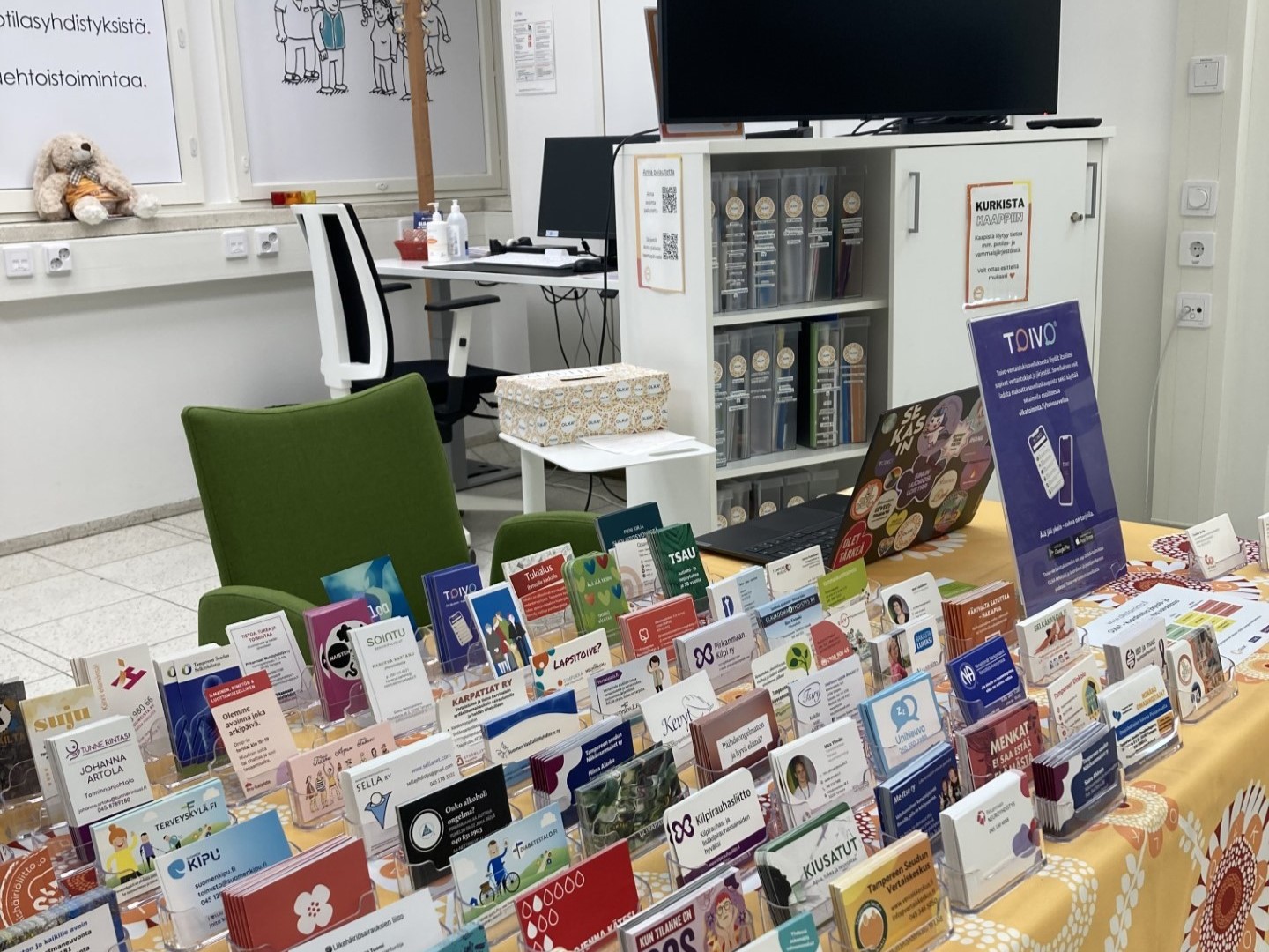 Tays Keskussairaalan OLKA-pisteellä oleva pöytä, johon aseteltu suuri määrä eri yhdistysten käyntikortteja.