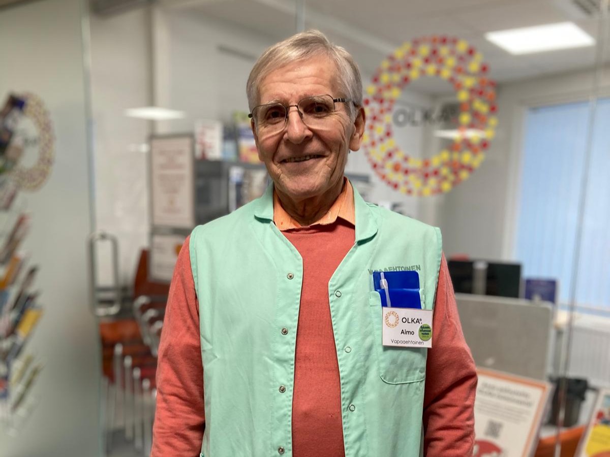 Sairaalavapaaehtoinen Aimo hymyilee kameralle OLKA-pisteellä.