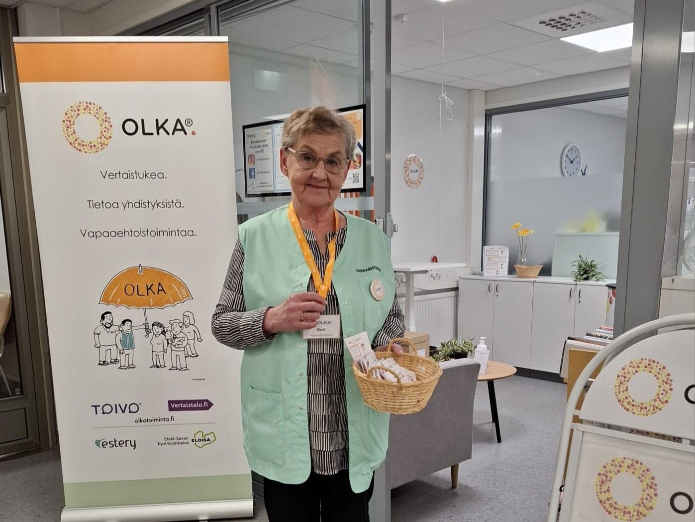 Vapaaehtoinen hymyilemässä OLKA-pisteellä.