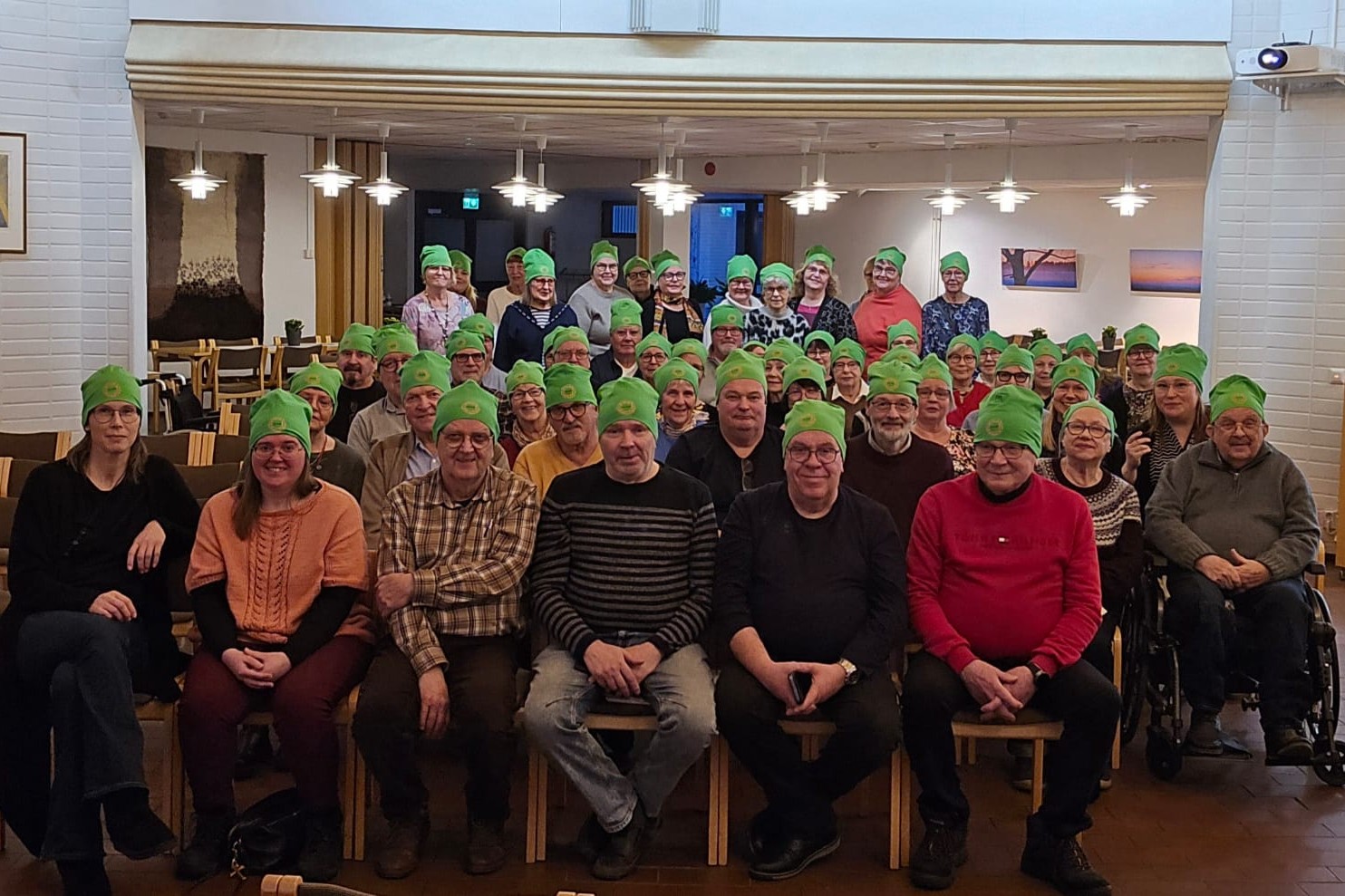 Seinäjoen OLKAn vapaaehtoisia starttipäivässä 2026. Vapaaehtoisia on suuri joukko ja heillä on päässään vihreät pipot, joissa on OLKAn logo.