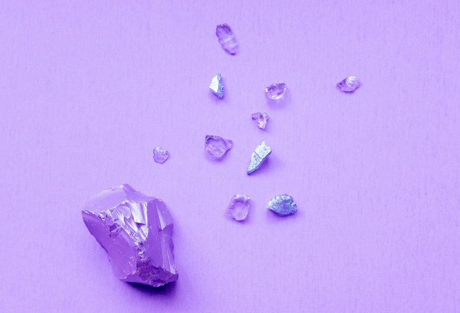 Vaaleanvioletteja, kristalleja muistuttavia kivikiteitä vaaleanvioletilla taustalla.