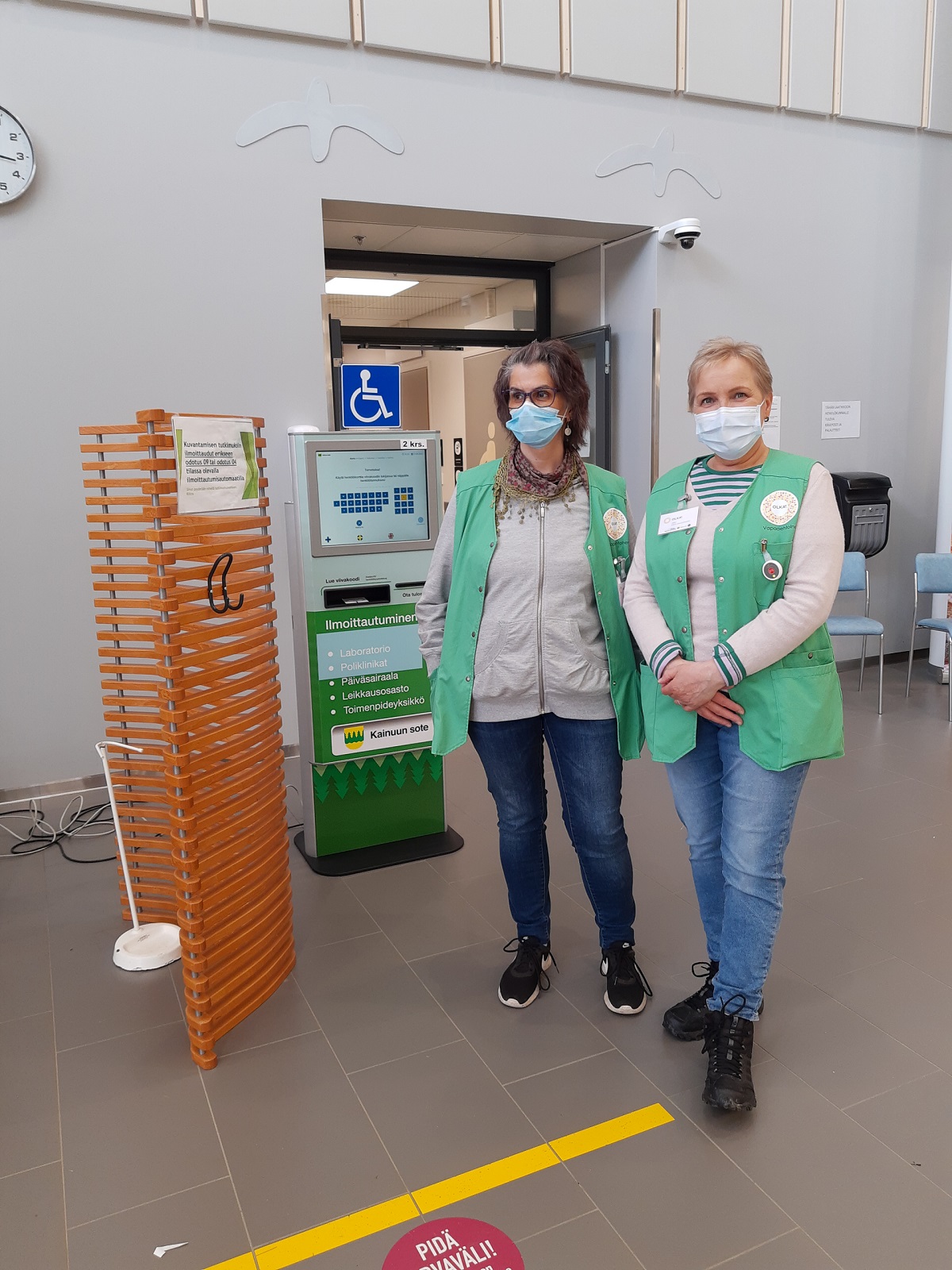 Uudet OLKA-vapaaehtoiset valmiina opastamaan sairaalan asiakkaita ilmoitusautomaattien käytössä.
